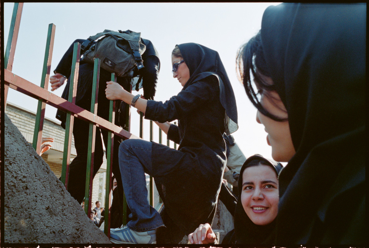 This is the first time I saw other girls climbing a fence to join a studentprotest. (Tehran, 1999) © Newsha Tavakolian